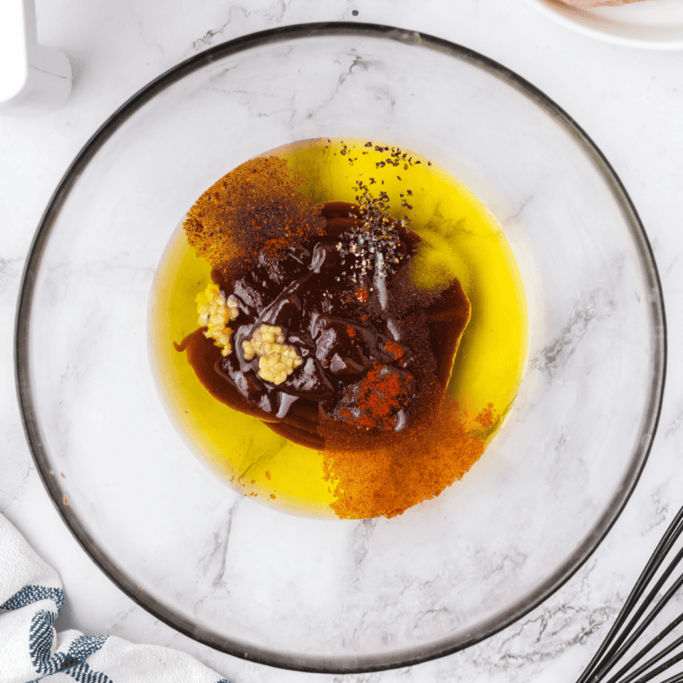 Whisking homemade honey bourbon marinade in a bowl until glossy