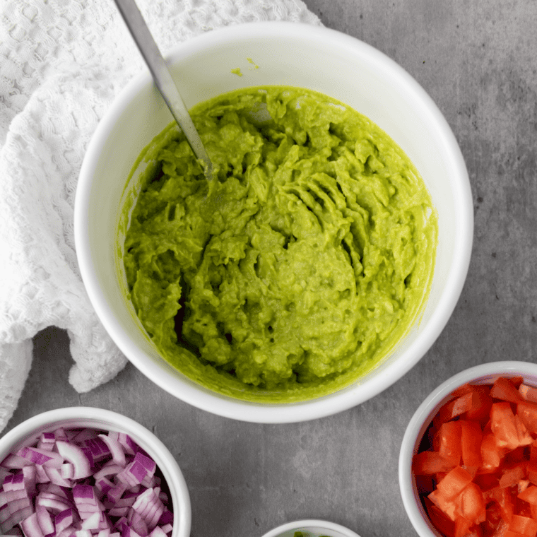 Avocado being mashed with a fork after adding lime juice and salt, kept slightly chunky