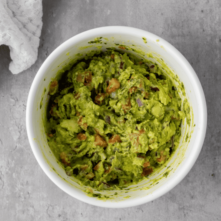 Finished guacamole being seasoned with extra salt and a squeeze of lime to taste