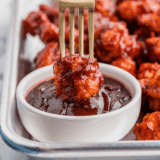 Jack Daniel's sauce in a glass jar with a spoon drizzling the glaze