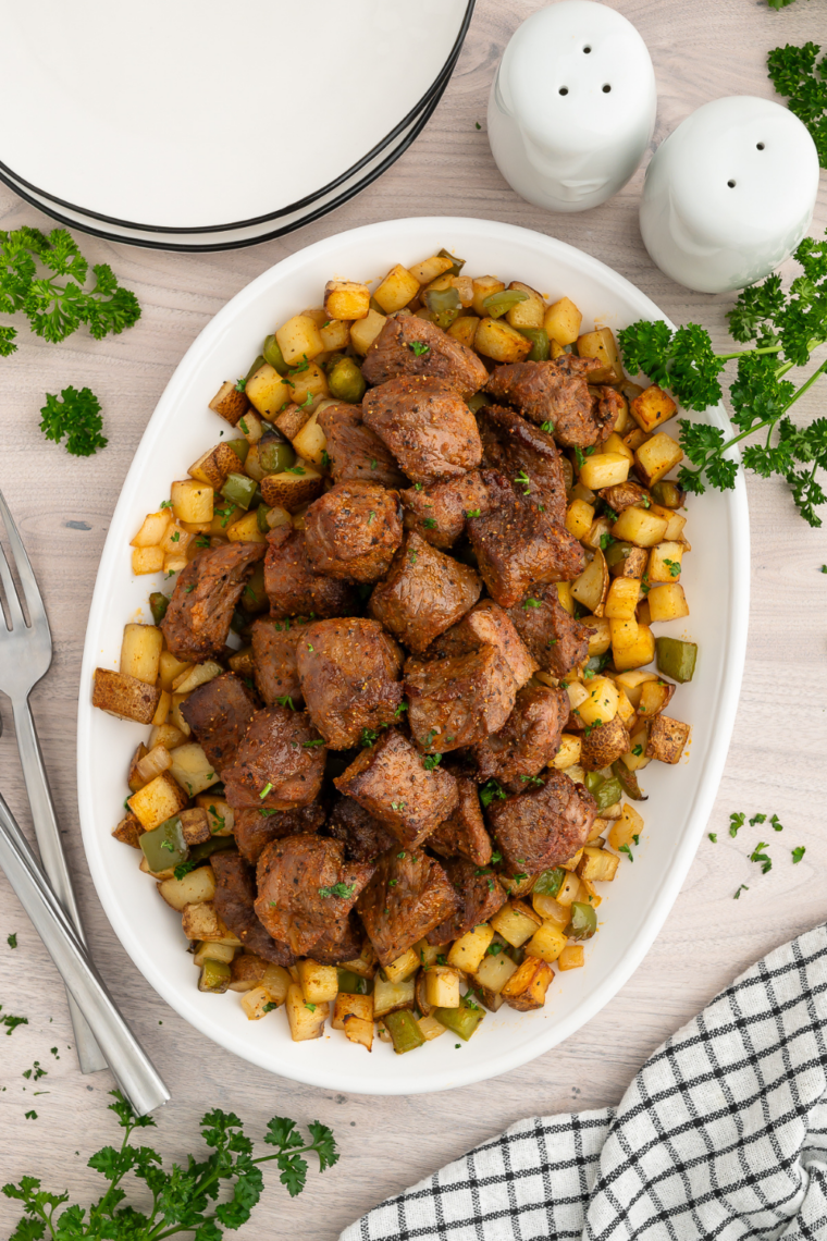 Air fryer steak bites and crispy potatoes served on a plate with green beans and garlic toast