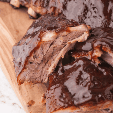 Baby back ribs in the oven glazed with barbecue sauce on a white plate
