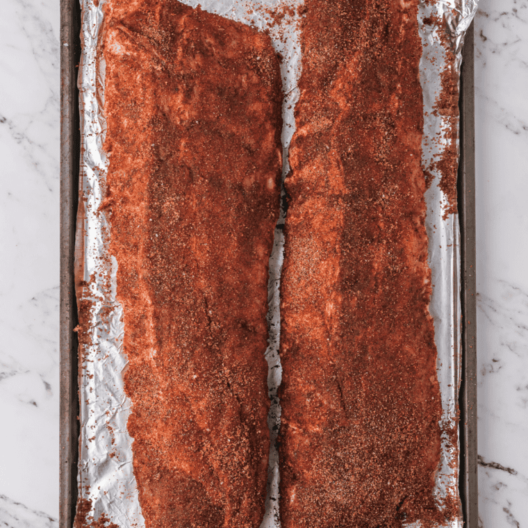 Baby back ribs coated with mustard and dry rub before baking in the oven