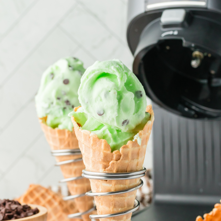 Scoop of green mint chocolate chip ice cream lifted from the pint, dark chocolate shards visible in the cross section.