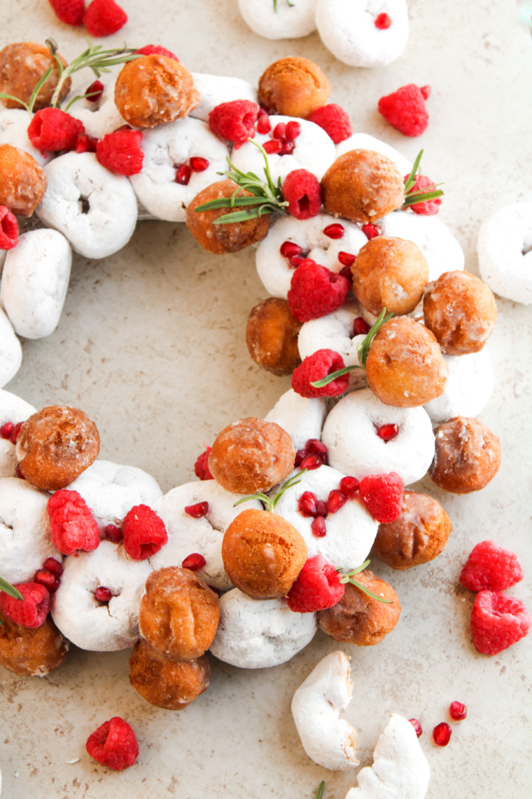 Fresh raspberries pressed into open spaces between the donuts on a holiday donut wreath
