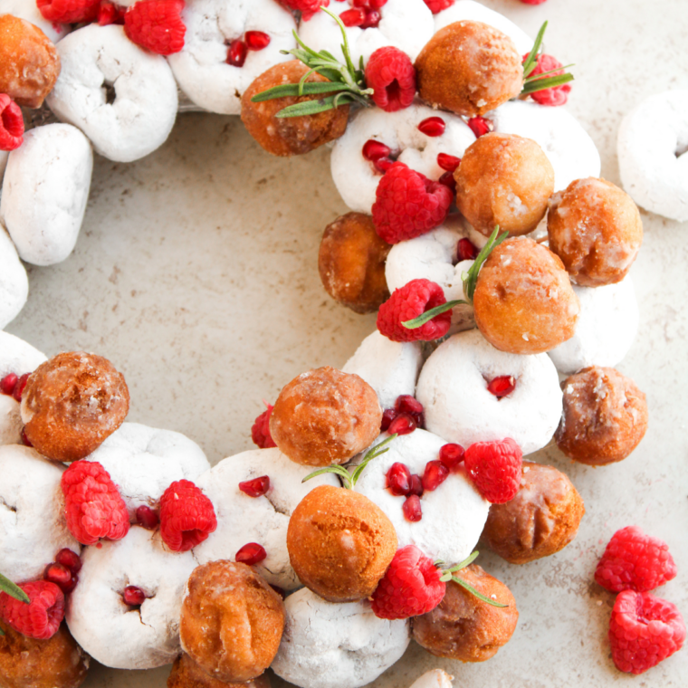 Finished donut wreath used as an edible holiday centerpiece on a Christmas dessert table