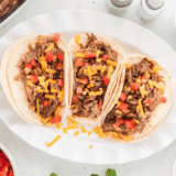 Plate of pork tacos seasoned with copycat McCormick al pastor seasoning, garnished with fresh lime and diced pineapple
