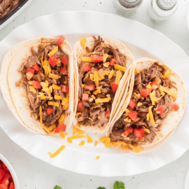 Plate of pork tacos seasoned with copycat McCormick al pastor seasoning, garnished with fresh lime and diced pineapple