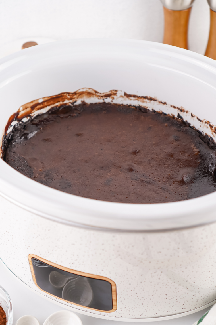 Spoonful of crock pot chocolate cobbler lifted from the slow cooker with fudge sauce running off the cake