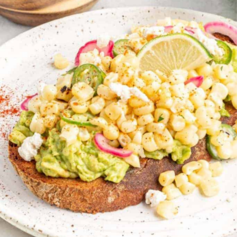 Finished homemade street corn seasoning sprinkled over grilled corn toast with cotija cheese and lime