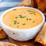 Bowl of copycat Ken's Boom Boom Sauce with visible red pepper and shallot flecks, served with crispy fries
