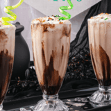 Ninja Slushi chocolate milkshake in a tall glass topped with whipped cream and chocolate syrup