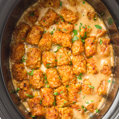 Slow cooker cowboy casserole topped with crispy golden tater tots and melted cheddar cheese