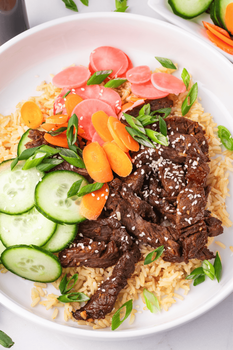 Overhead view of two Korean beef bulgogi bowls topped with sesame seeds and scallions