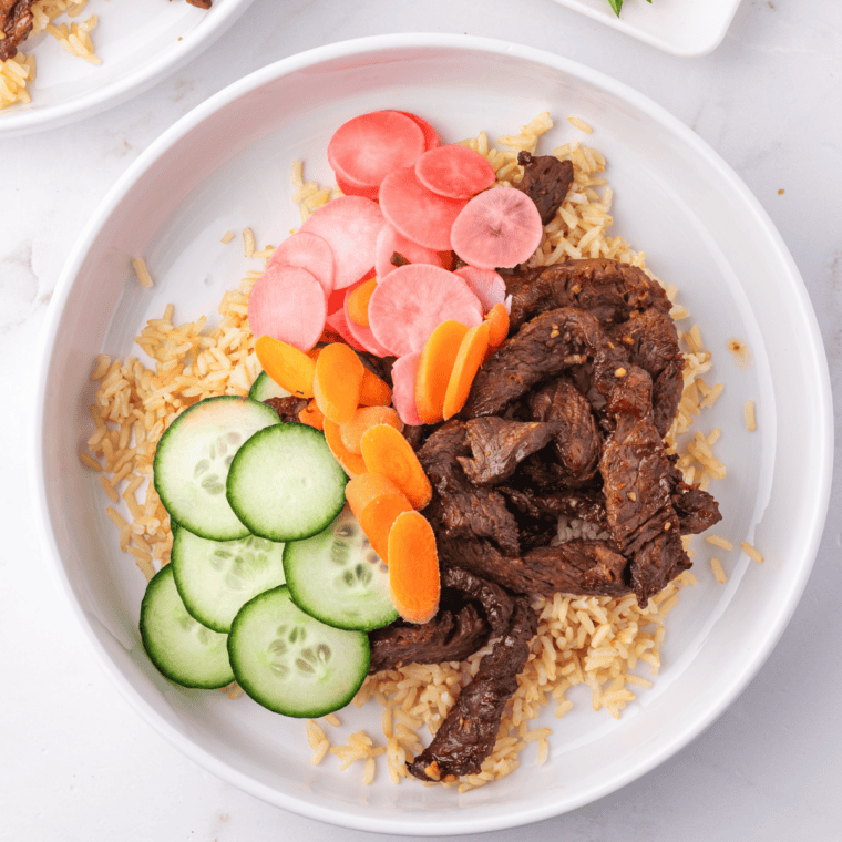 Air fryer bulgogi beef spooned over rice and topped with scallions and sesame seeds