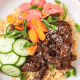 Air fryer bulgogi beef bowl with rice, scallions, sesame seeds, cucumber, and pickled radish
