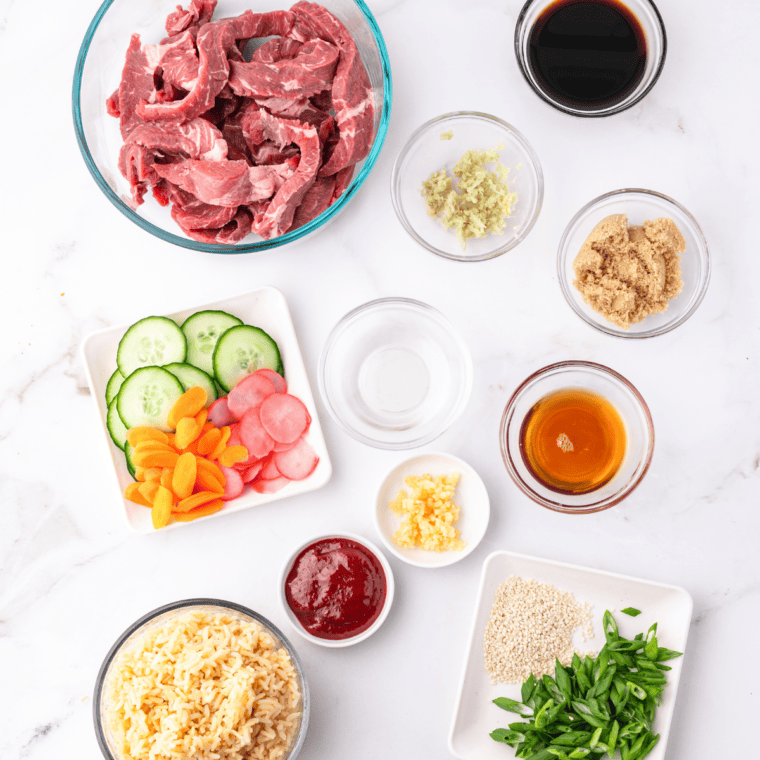 Ingredients for air fryer bulgogi bowls: sliced beef, soy sauce, brown sugar, sesame oil, gochujang, garlic, ginger, rice, and scallions