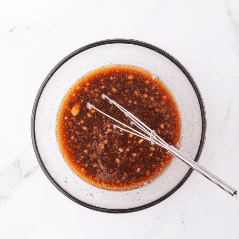 Whisking soy sauce, brown sugar, gochujang, garlic, and ginger together in a glass bowl