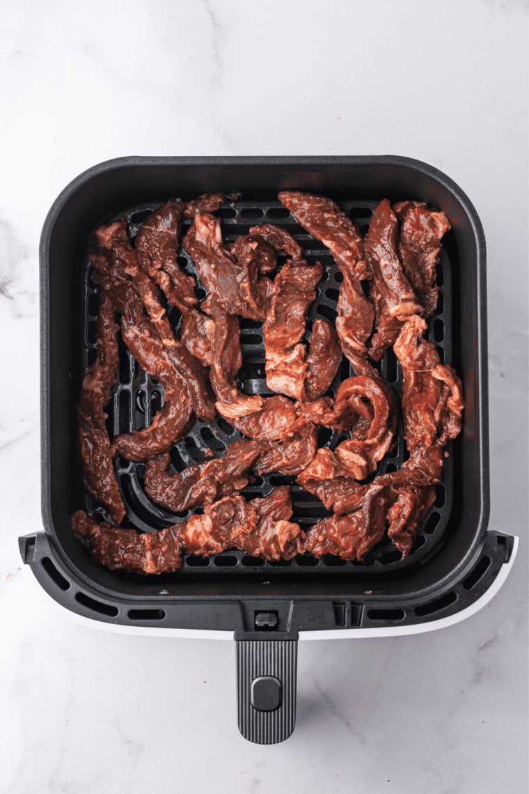 Marinated bulgogi beef arranged in a single layer in an air fryer basket