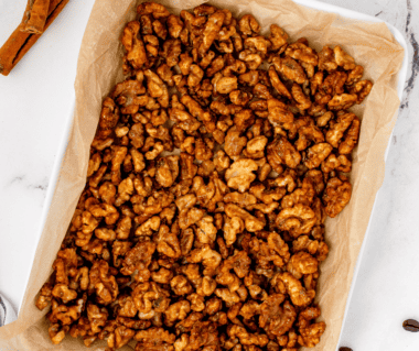 Air fryer candied coffee walnuts cooling in a single layer on a parchment-lined baking sheet