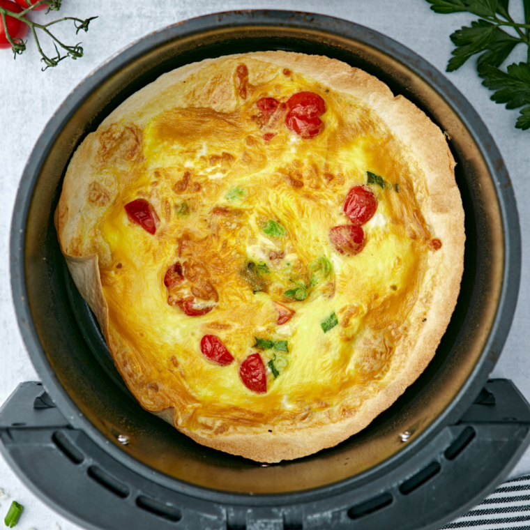 Cooked air fryer egg tortilla frittata in the basket, center set and edges golden brown
