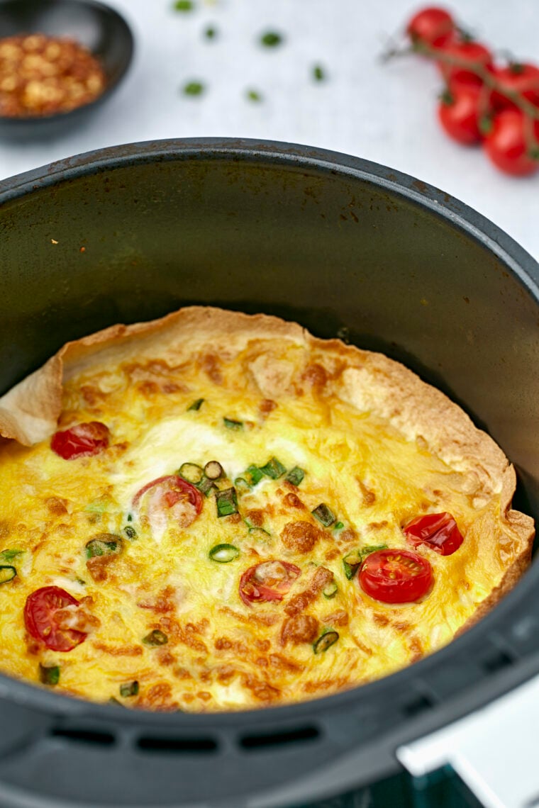 Golden frittata with melted cheese finished cooking inside the air fryer basket