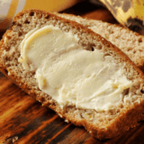 banana bread recipe Bob Evans style sliced on a wooden board showing walnuts throughout