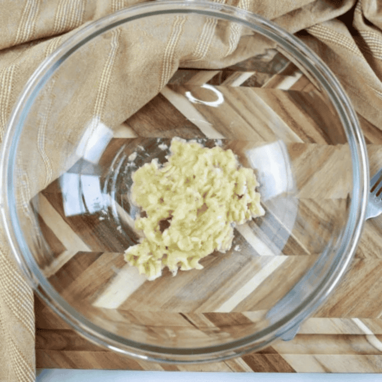 Very ripe black bananas mashed with a fork in a large glass bowl, still slightly lumpy