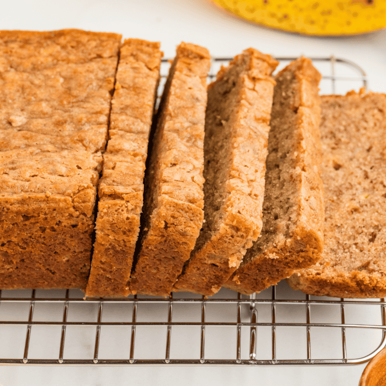 Sliced copycat Bob Evans banana nut bread on a wooden board showing the moist crumb and walnuts