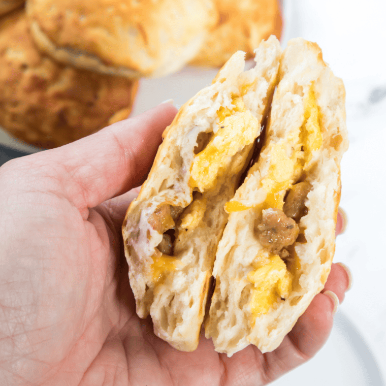 Stack of golden-brown Bob Evans breakfast sausage patties on a white plate with scrambled eggs and a biscuit