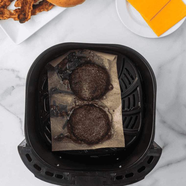 Breakfast sausage patties searing in a dry cast iron skillet, browned crust on the flipped side