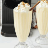 Copycat Chick-fil-A Autumn Spice Milkshake topped with whipped cream, crushed brown sugar cookies, and a cherry in a tall glass