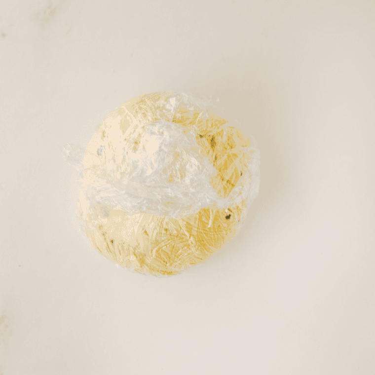 Chocolate chip cheese ball mixture wrapped in plastic wrap and twisted into a ball