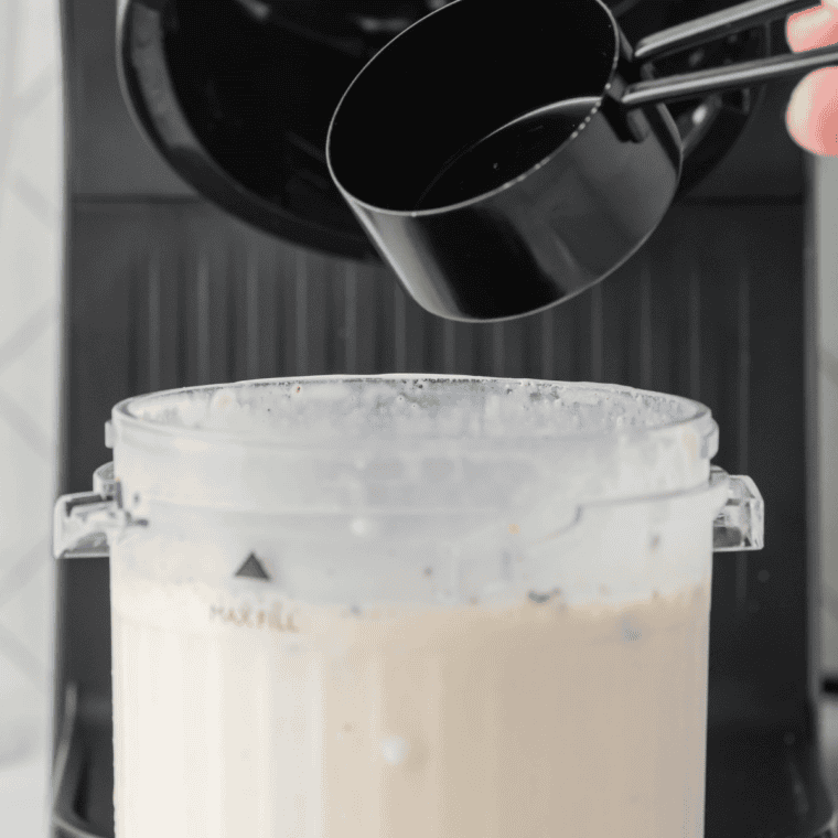 Scoops of vanilla ice cream and vanilla extract added to milk in a blender jar