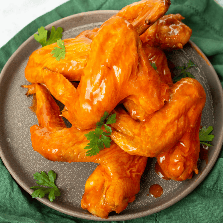 Crispy chicken wings coated in homemade copycat Frank's RedHot sauce on a gray plate