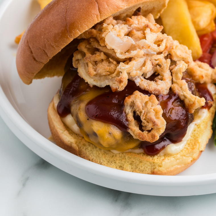 whiskey BBQ burger topped with crispy fried onions and steak fries on the side