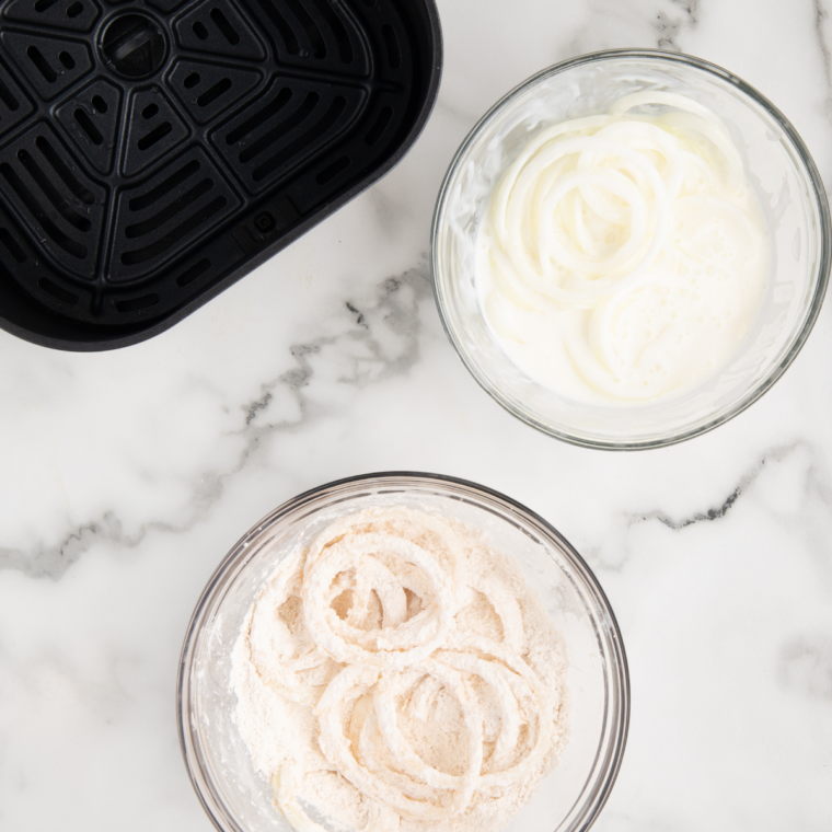 flour coated onions in a single layer in an air fryer basket
