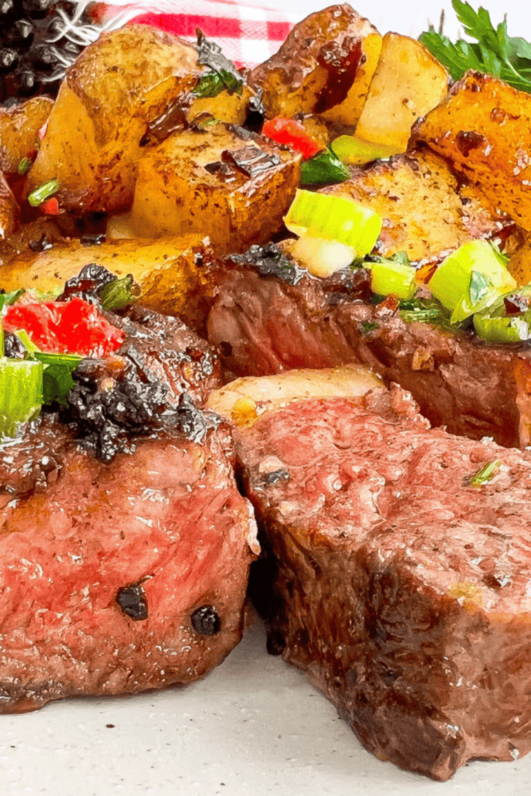 Sliced steak on a plate beside a jar of copycat Kinder's Buttery Garlic and Herb seasoning