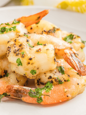 Lemon pepper shrimp arranged on a white plate with lemon wedges