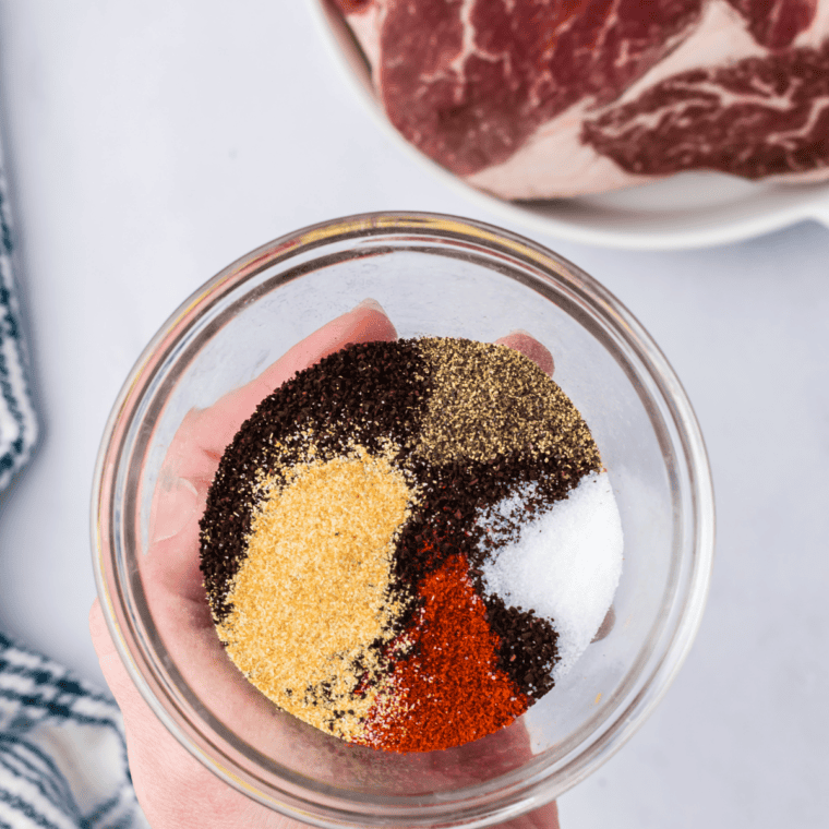 Granulated garlic, smoked paprika, salt, brown sugar and spices in bowls for woodfired garlic seasoning