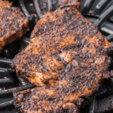 Ribeye steak coated in copycat Kinder's Woodfired Garlic seasoning grilling over open flame