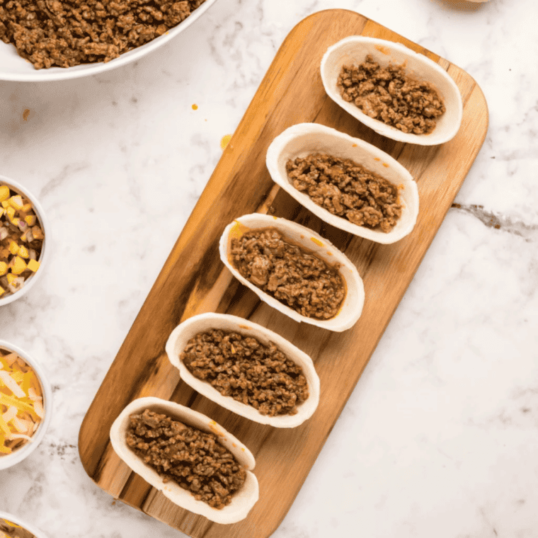Seasoned taco meat spooned into crispy taco cups