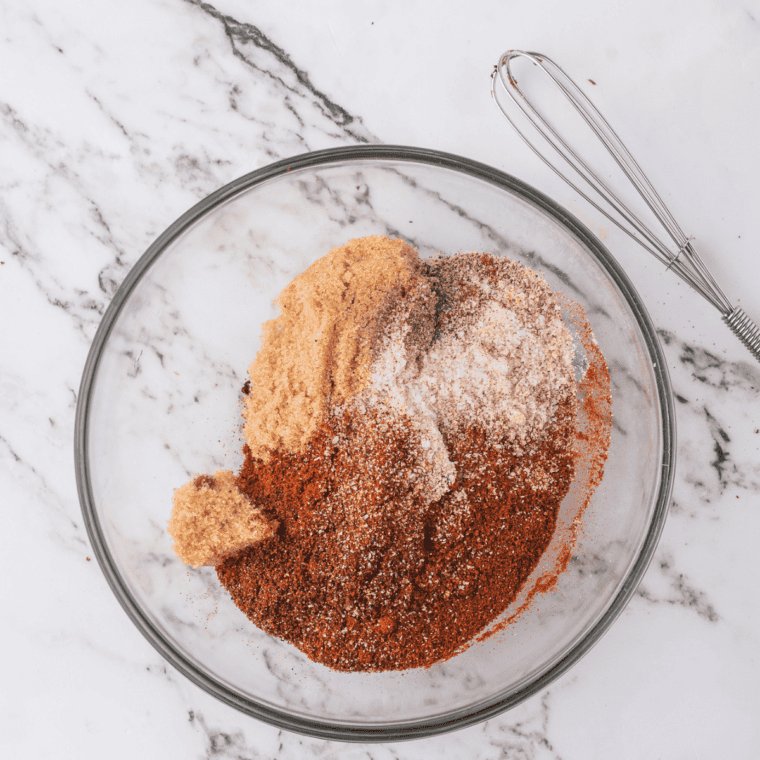 Whisking paprika, turmeric, salt, and spices together in a small white bowl until the blend turns uniform golden