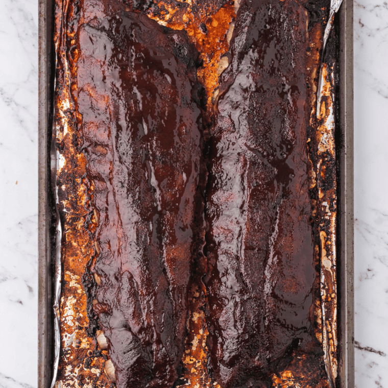 Whole rack of ribs seasoned with copycat LongHorn Prairie Dust, cooked and resting on a wooden cutting board