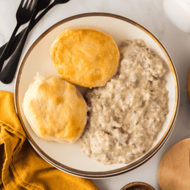 Homemade sausage gravy ladled over split biscuits with visible black pepper