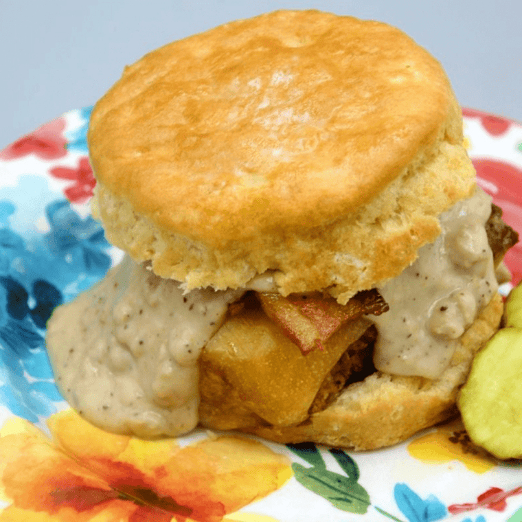 Biscuits and country gravy on a plate with fried eggs and sausage, shot from above