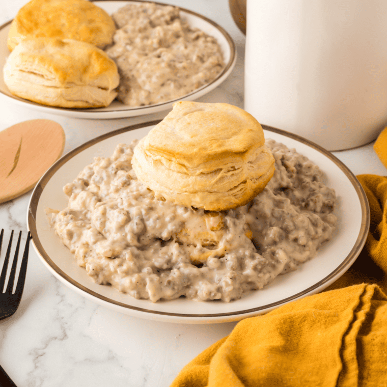 Copycat McCormick country gravy poured over split biscuits on a white plate
