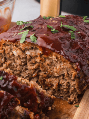Sliced copycat McCormick meatloaf with ketchup glaze on a wooden cutting board