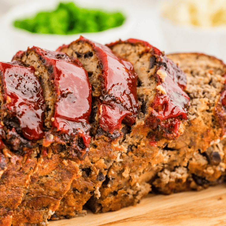 Whole glazed meatloaf on a wooden cutting board, made with copycat McCormick meatloaf seasoning