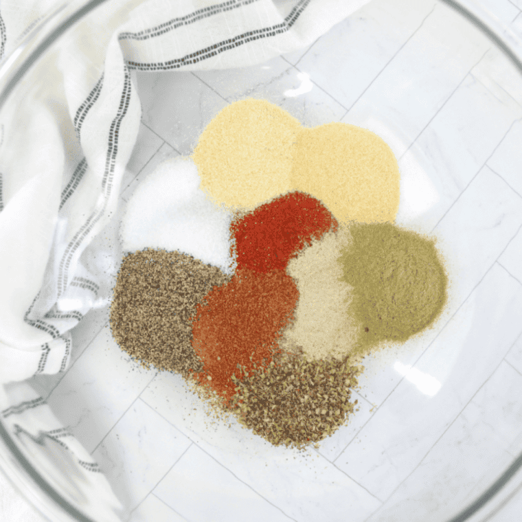 Dried minced onion, paprika, celery seed, mustard, and brown sugar measured out on a plate